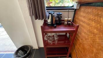 A wooden shelf with a coffee maker, jars, and glasses.