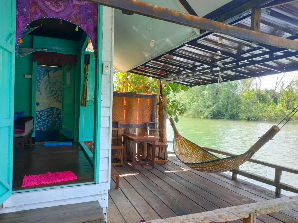 Una terraza de madera con una hamaca, una mesita y un banco.