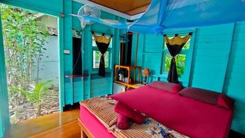 Une chambre avec un lit, un ventilateur et une vue sur la verdure.