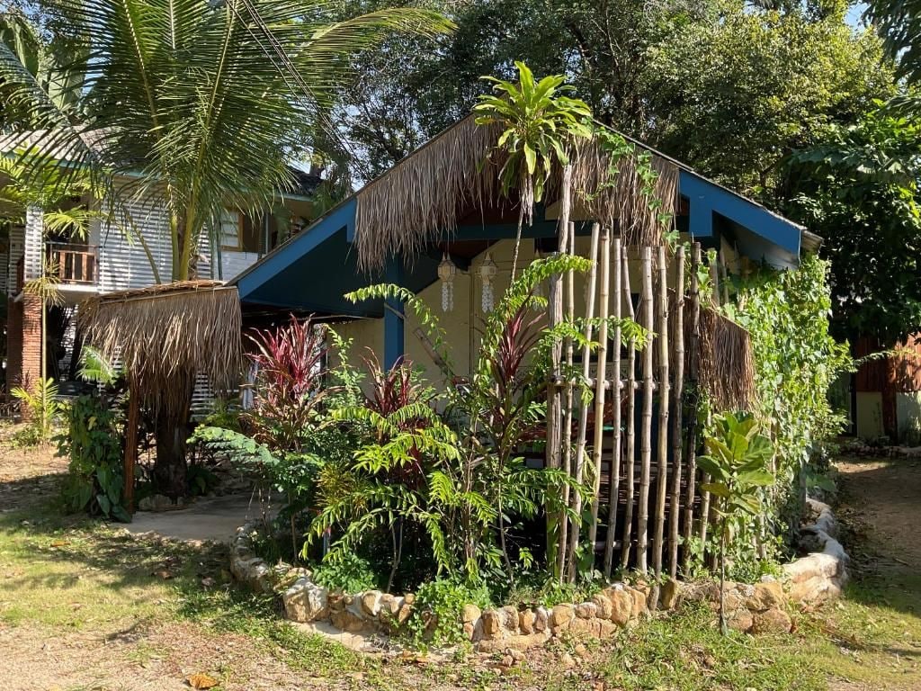 Una estructura tradicional con techo de paja rodeada de exuberante vegetación tropical.
