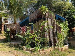 Una estructura tradicional con techo de paja rodeada de exuberante vegetación tropical.