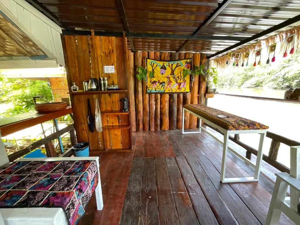 A wooden cabin with a bench and a table, a shelf with toiletries, and a colorful wall hanging.