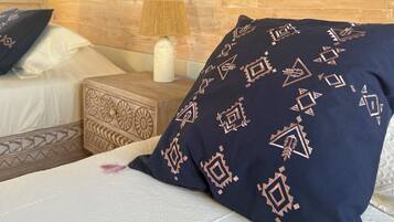 A bed with a patterned pillow, a bedside table with a lamp, and a wooden headboard.