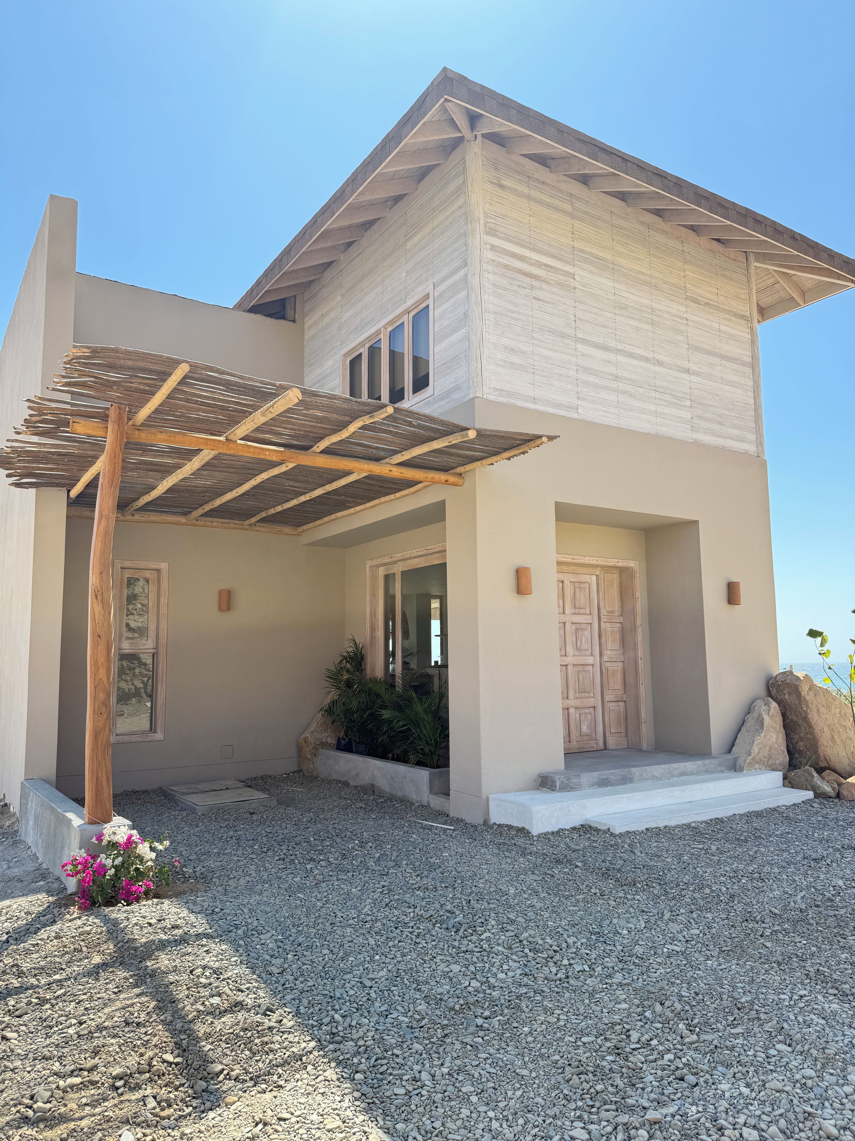A modern two-story house with a covered patio, a front door, and a small garden.