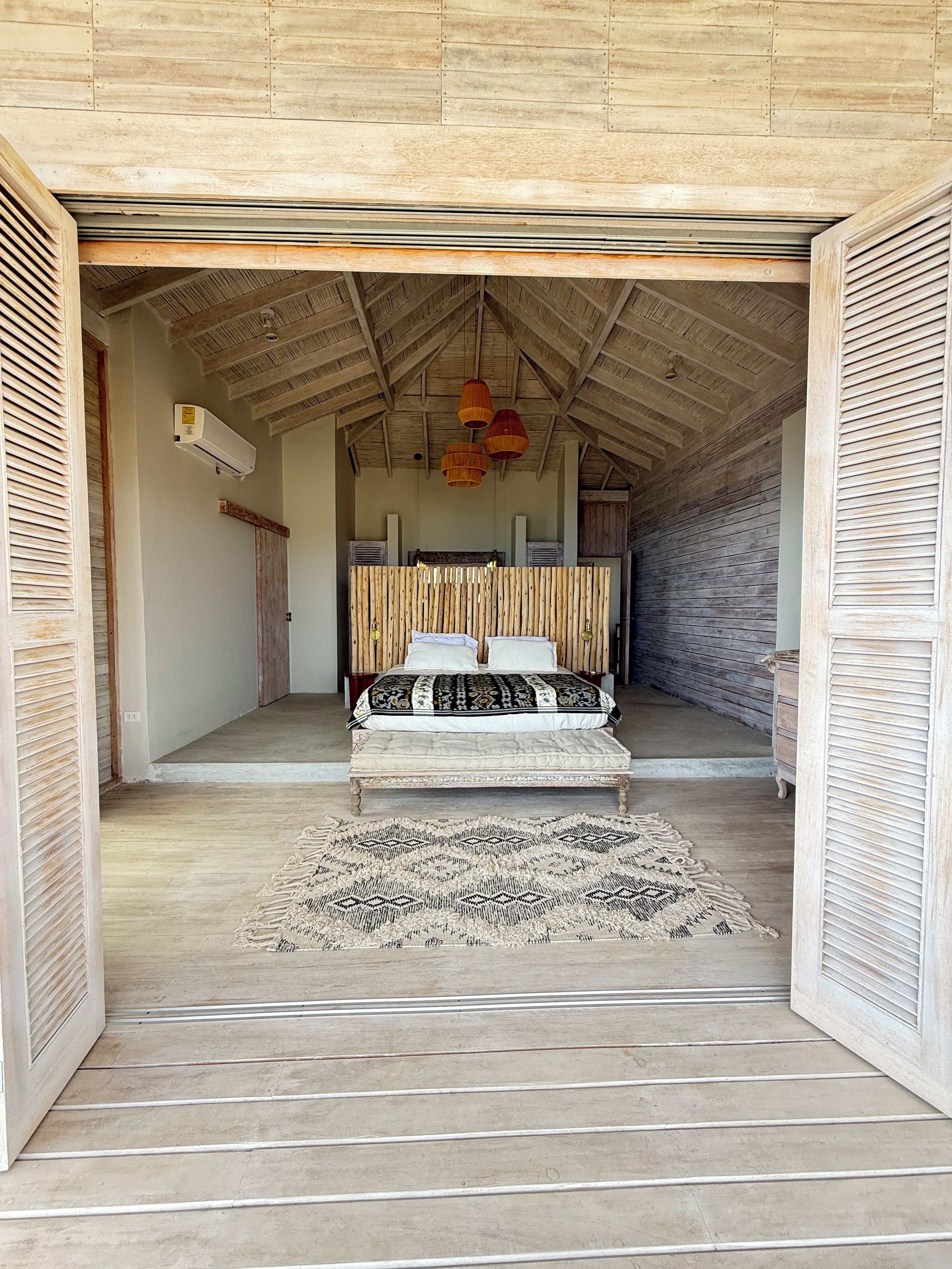 Un dormitorio con una cama, techo de madera y alfombra estampada.