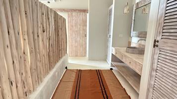 A hallway with a wooden wall, a brown rug, and a door with a mirror.