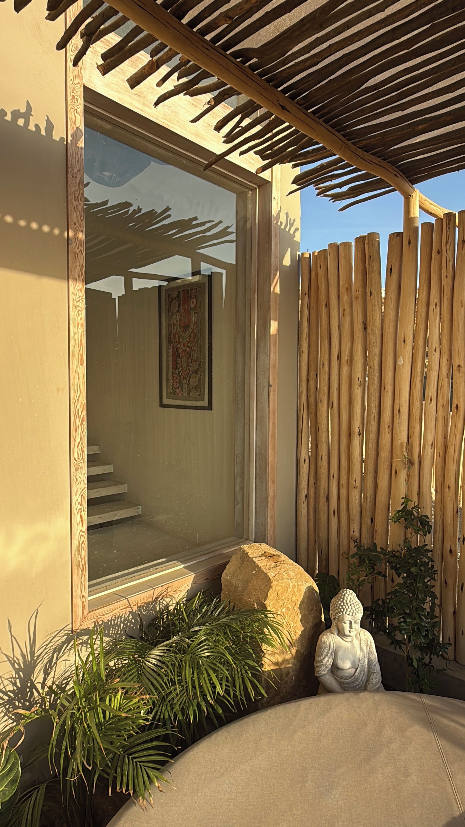 Une clôture en bois, une statue de Bouddha et une grande fenêtre donnant sur un escalier.
