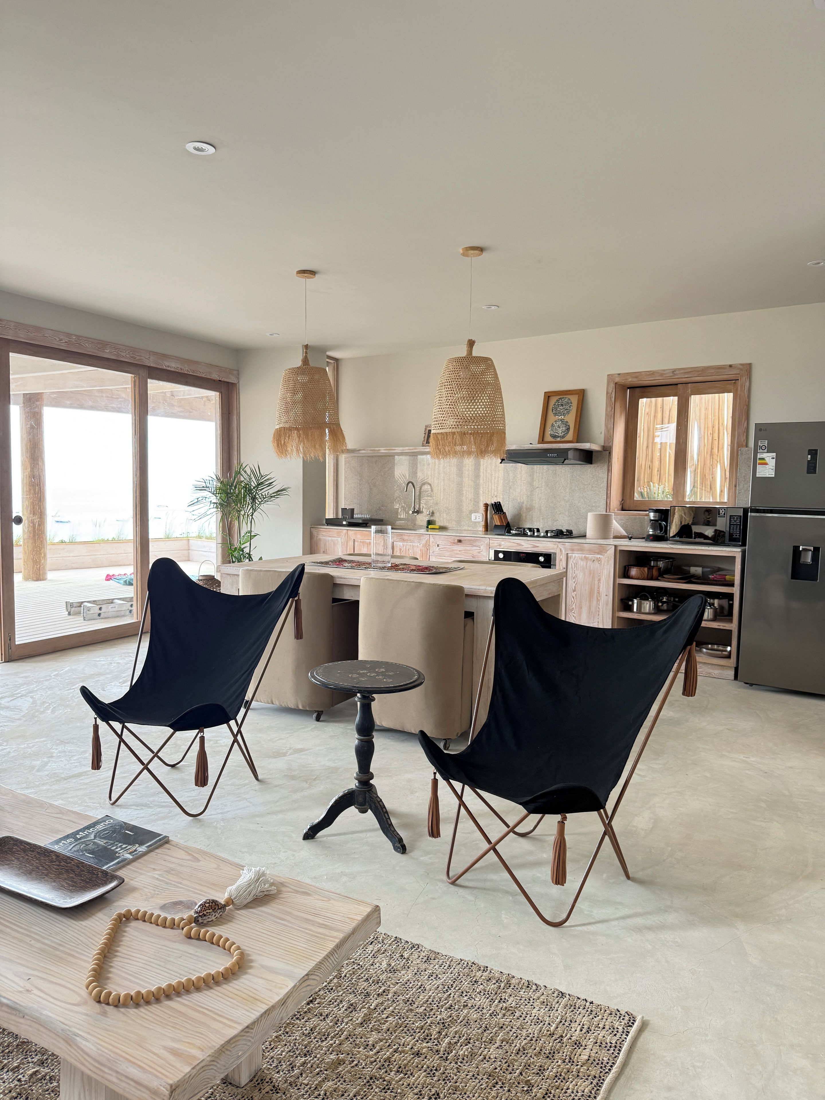 A modern kitchen with a dining area, two chairs, a table, and a hanging light fixture.
