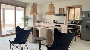 A modern kitchen with a dining area, two chairs, a table, and a hanging light fixture.