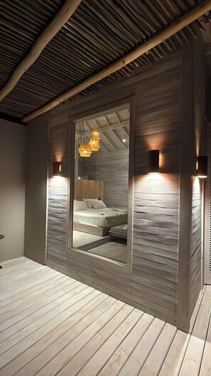Ein Schlafzimmer mit einem großen Spiegel, Holzlatten an den Wänden und einem Bett mit Kissen.