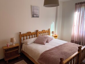 A bed with a wooden headboard, a bedside table with a lamp, and a bedside plant. - AffittiPontediLegno - Sorgente (Ponte di legno)