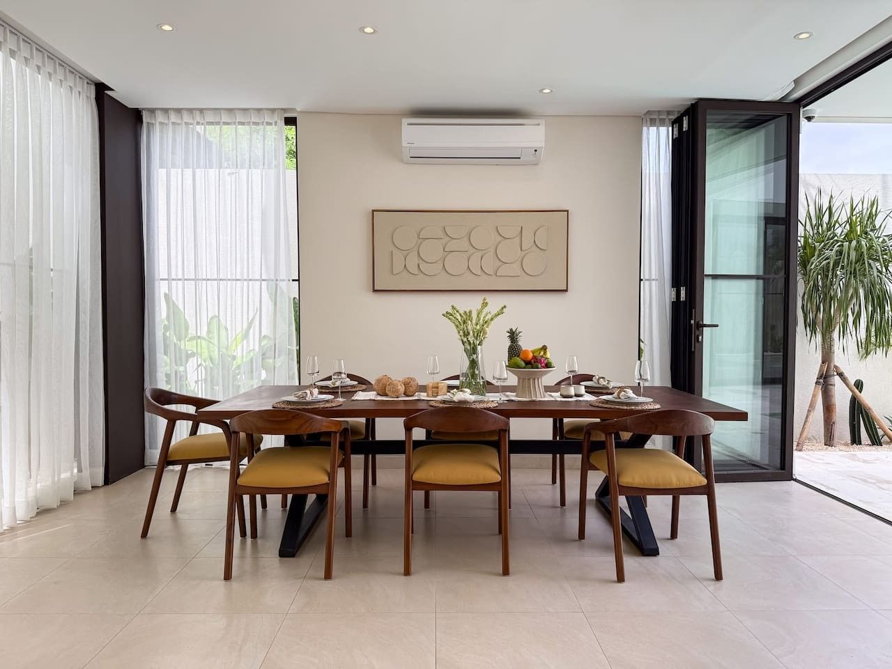 A dining area with a table set for six, surrounded by chairs with cushions.