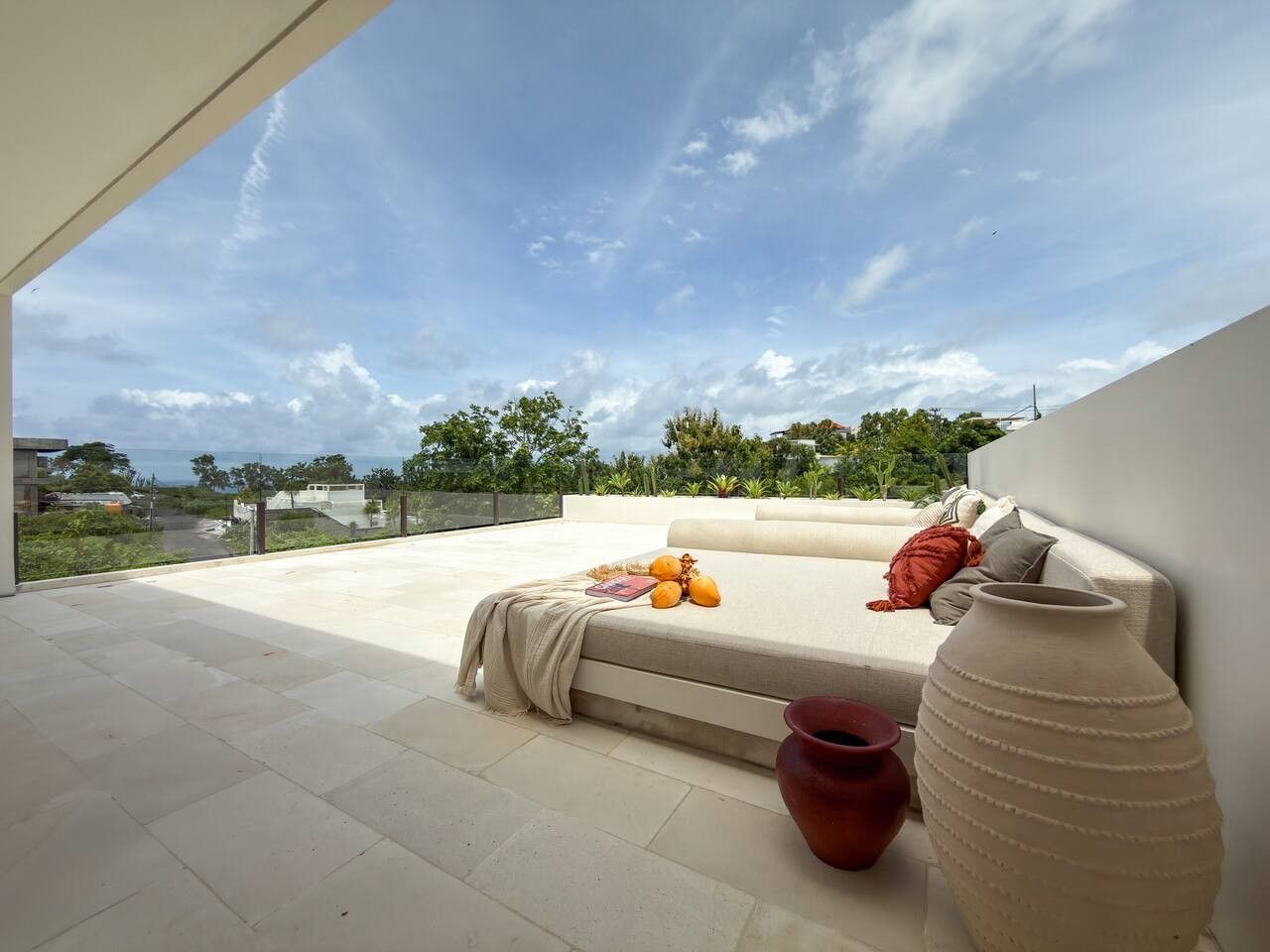 A rooftop terrace with a sofa, a large vase, and a bowl of fruit.