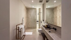 Un baño moderno con un espejo grande, un tocador de madera y una zona de ducha.
