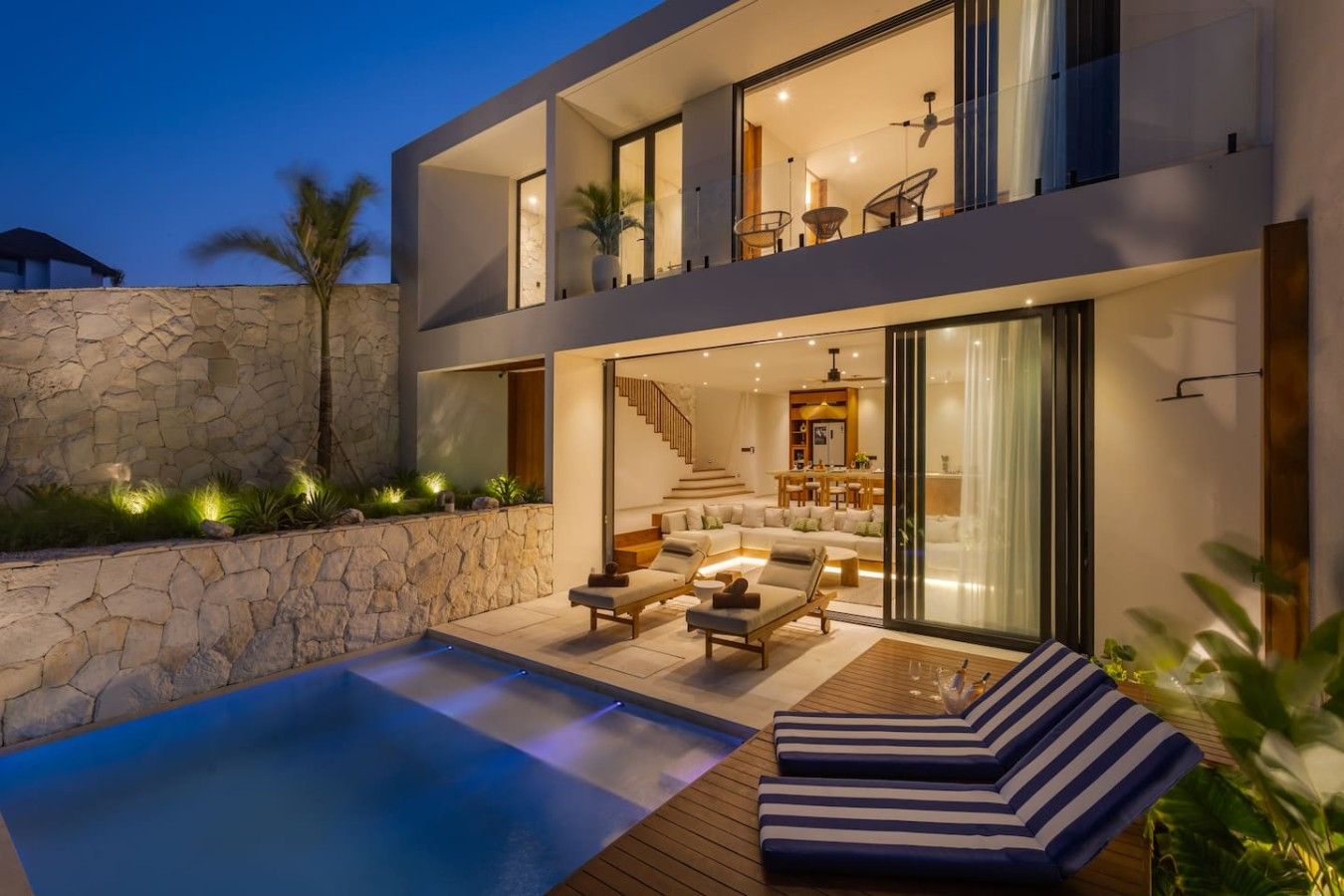 A modern two-story house with a swimming pool, outdoor seating, and a staircase leading to the upper floor.