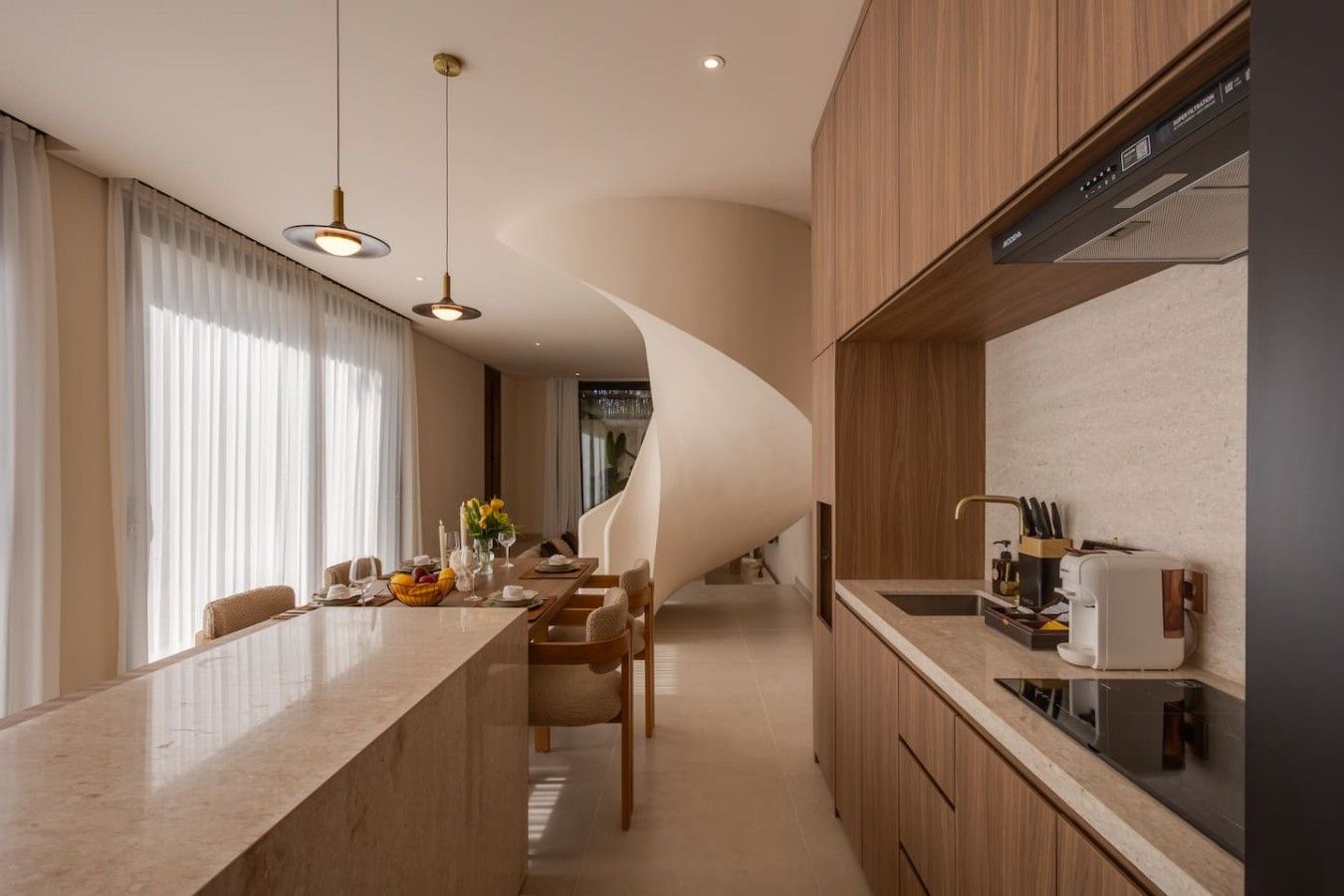 A modern kitchen with a curved island, wooden cabinets, and a built-in stove.