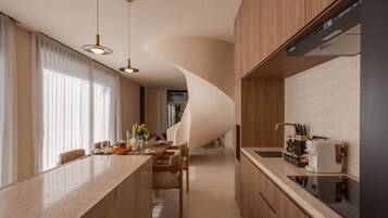 A modern kitchen with a curved island, wooden cabinets, and a built-in stove.
