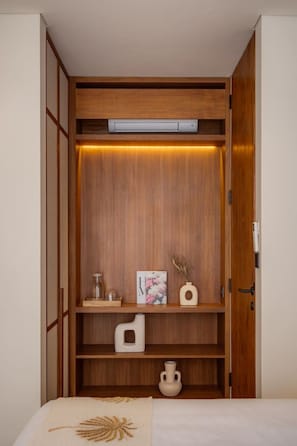 A walk-in closet with wooden shelving, a hanging rod, and a small table with decorative items. - NEW 4BR Luxury Villa in the Heart of Bingin (South Kuta)