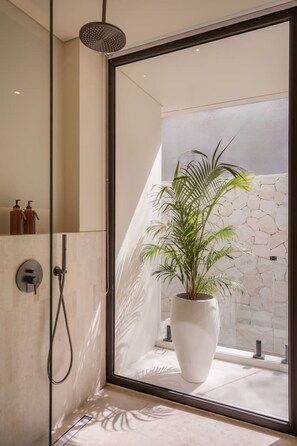 Ein modernes Badezimmer mit Duschkabine aus Glas, einer Topfpflanze und einer Steinwand.