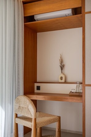 Un bureau en bois, une chaise en osier, un petit vase et un haut-parleur.