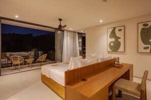 Une chambre moderne avec un lit, un bureau en bois et un balcon équipé de chaises.