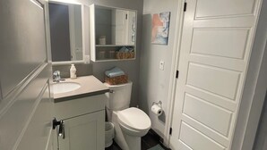 Een badkamer met toilet, wastafel, spiegel en kastruimte.