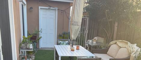 A backyard with a white table, a wooden chair, and a covered umbrella.