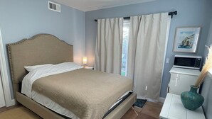 Een slaapkamer met een bed, nachtkastje en een klein kastje.