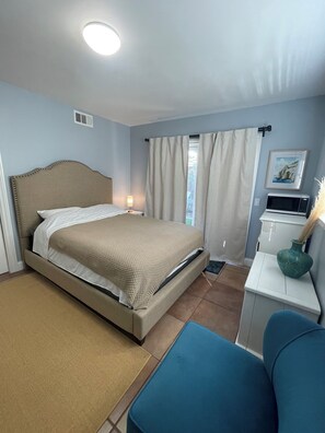 Un dormitorio con cama, mesita de noche y un armario pequeño.