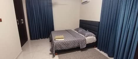 Un dormitorio con cama, cortinas, ventilador de techo y aire acondicionado.