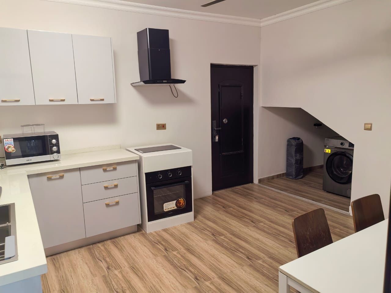 A compact kitchen with a microwave, oven, and washing machine.