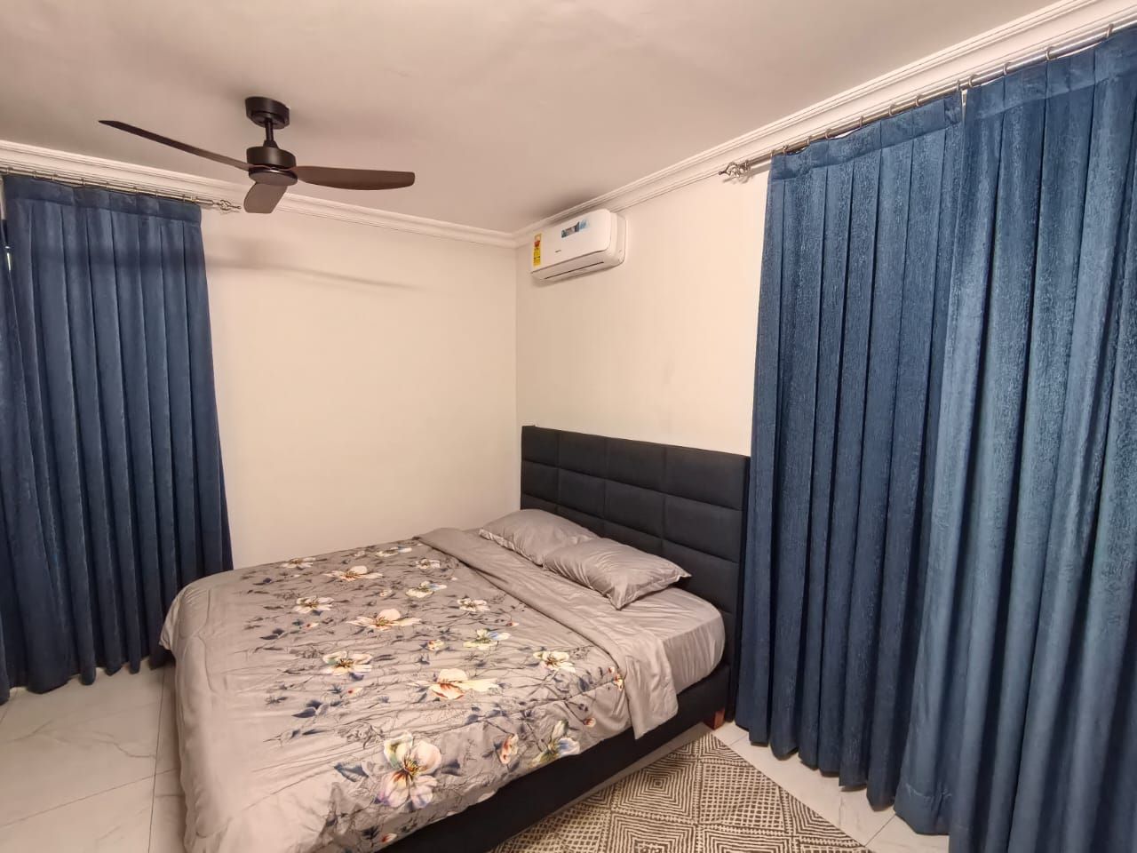 Ein Schlafzimmer mit Bett, Vorhängen, Deckenventilator und Klimaanlage.