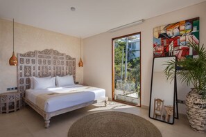 A bedroom with a large bed, a wooden headboard, a large mirror, and a view of greenery outside. - 1BR Ocean View Villa w/ Pool – Bingin (South Kuta)