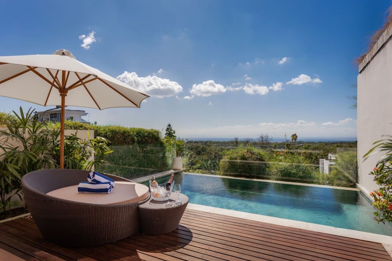 A poolside area with a wicker lounge chair, a small round table, and an umbrella.