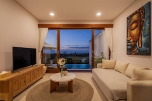 A living room with a television, sofa, coffee table, and a painting. - 1BR Ocean View Villa w/ Pool – Bingin (South Kuta)