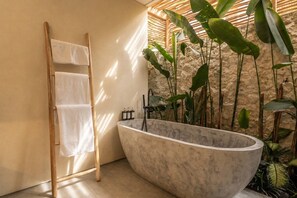 Ein Badezimmer mit einer freistehenden Badewanne, einer Holzleiter und einem an der Wand befestigten Handtuchhalter.