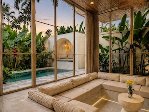 Ein modernes Interieur mit einer großen Glaswand, einem Pool und einem beigefarbenen Sofa.