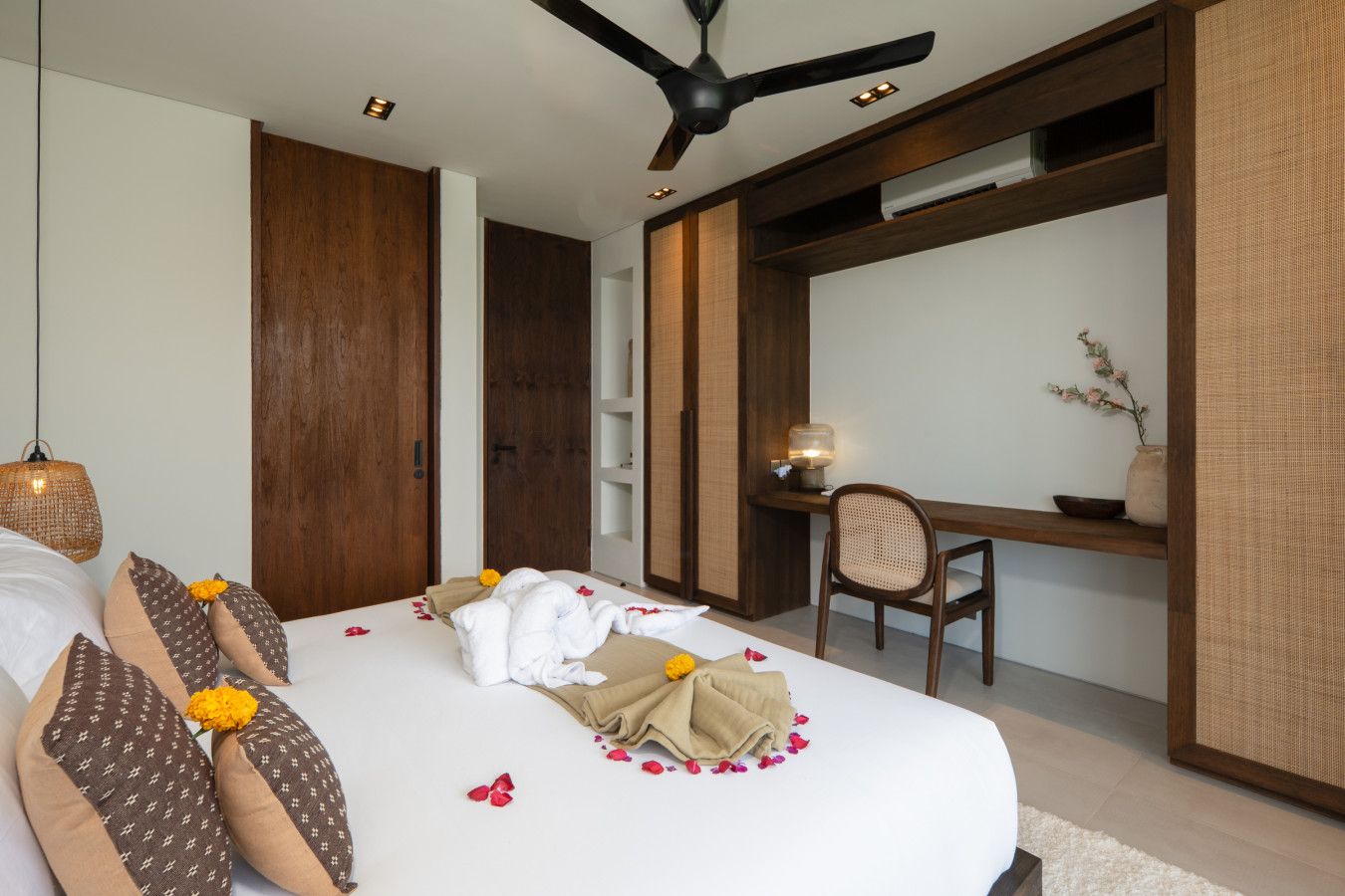 A bedroom with a bed, a desk, a chair, and a ceiling fan.