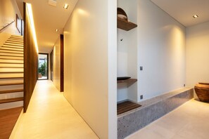 A modern interior with a wooden staircase, a kitchen area with a countertop, and a large pot. - Kulu Villa 4BR Luxury Villa with Rooftop - Uluwatu (South Kuta)