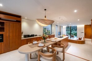 Een moderne keuken met een centraal eiland, houten kastjes en een hanglamp.