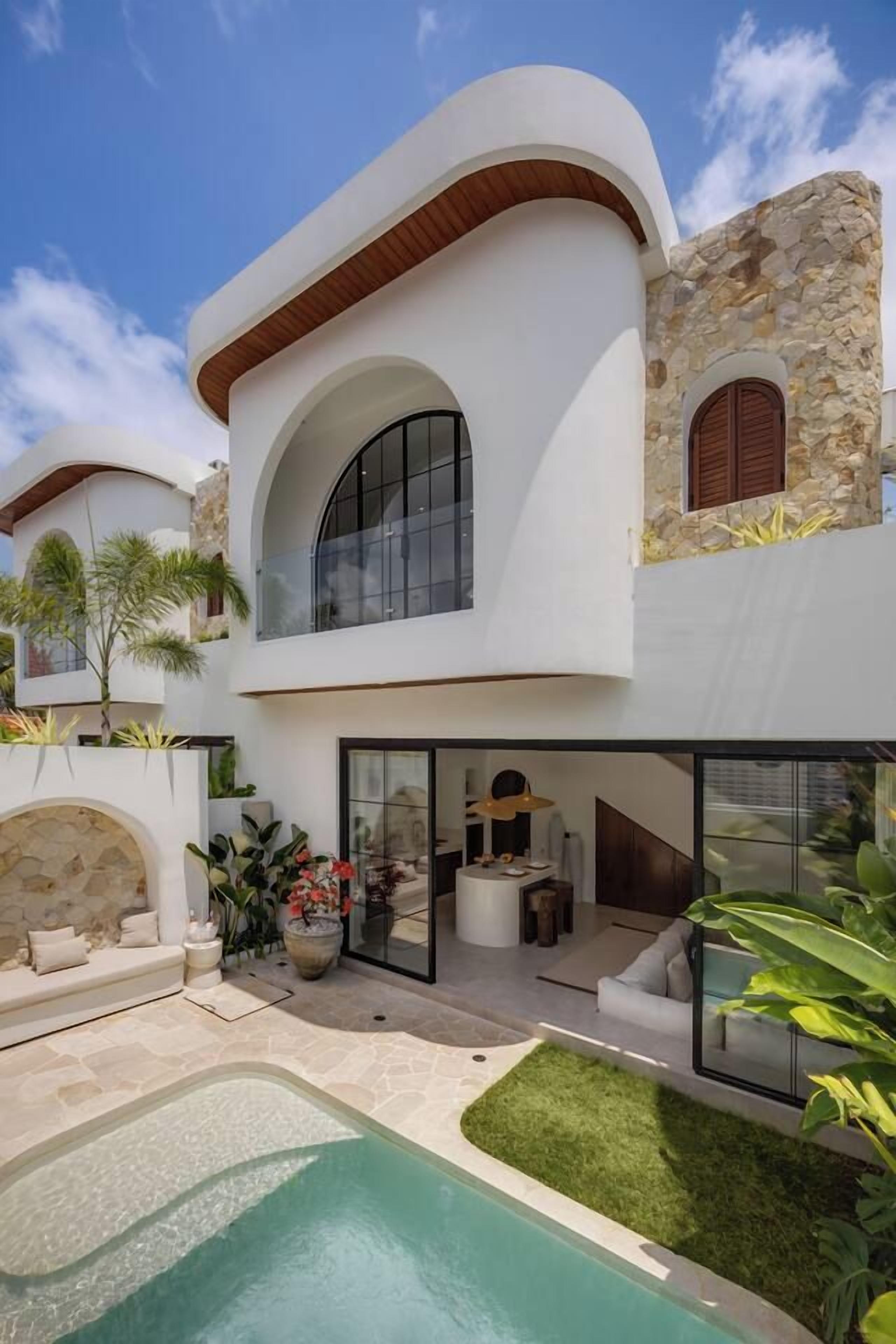 Una casa moderna de dos pisos con piscina, mobiliario exterior y fachada de piedra.