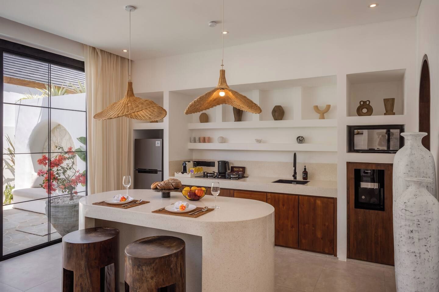 A modern kitchen with a central island, pendant lights, and a view of the outdoors.