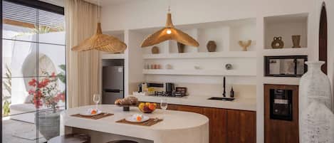A modern kitchen with a central island, pendant lights, and a view of the outdoors.