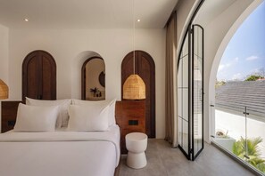 A modern bedroom with a large bed, a small seating area, and a balcony with a view. - Kaia 1BR Villa in the Heart of Bingin, Uluwatu (South Kuta)