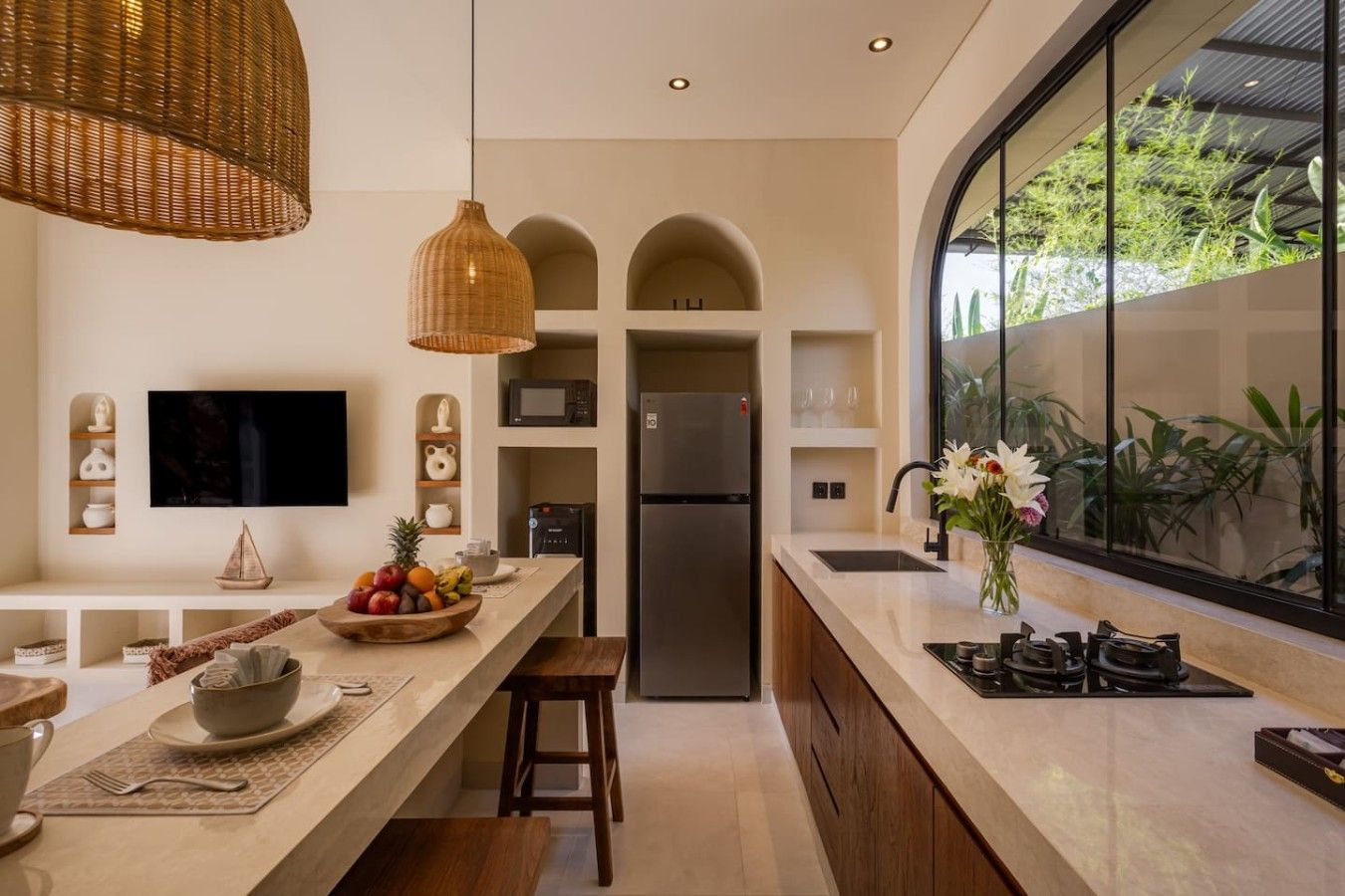 A modern kitchen with a large island, built-in appliances, and a view of greenery through a large window.