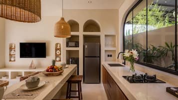 A modern kitchen with a large island, built-in appliances, and a view of greenery through a large window.