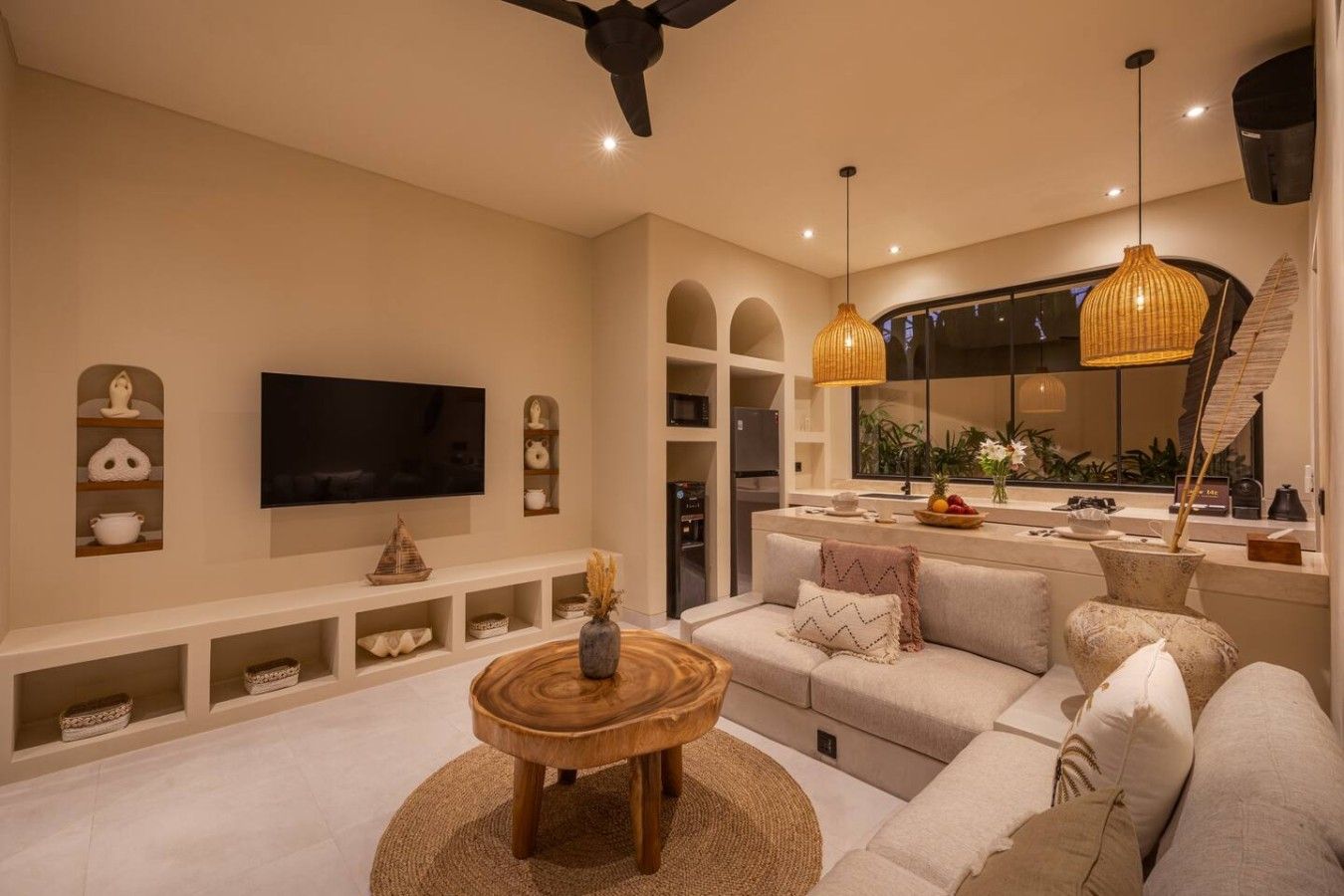 A modern living room with a flat-screen TV, a sofa, a coffee table, and a dining area with a kitchen counter.