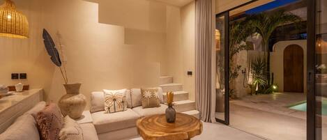 A modern living room with a sofa, a coffee table, and a staircase leading to a balcony.