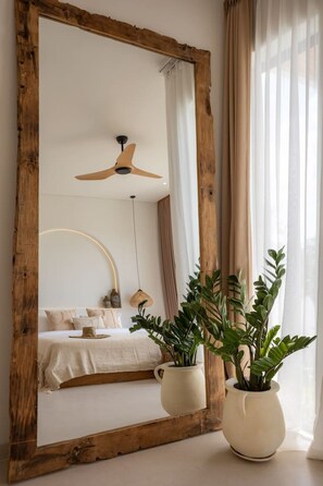 A bedroom with a large mirror, a ceiling fan, a bed with pillows, and two potted plants. - Roya 2BR Private Pool Villa w/ Jacuzzi in Bingin (Uluwatu)