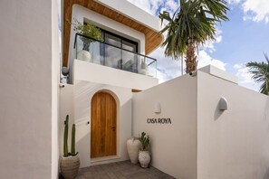 A modern two-story building with a wooden door, a balcony with glass railings, and a sign that reads 'CASA ROYA'. - Roya 2BR Private Pool Villa w/ Jacuzzi in Bingin (Uluwatu)